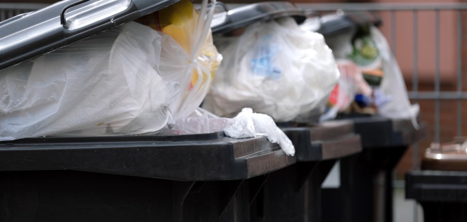 Vollgestopfte Mülltonnen an Mehrfamilienhaus durch mehr Müll wegen Corona - Stockfoto