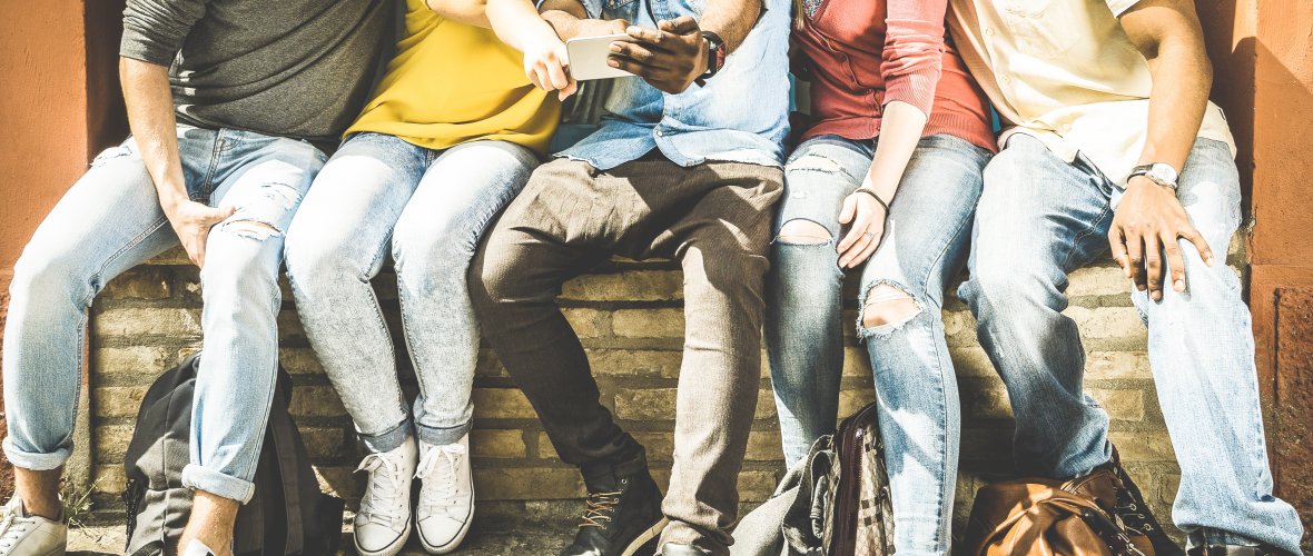 "Gruppe von multikulturellen Freunden, die auf einem urbanen Hintergrund Smartphones benutzen"